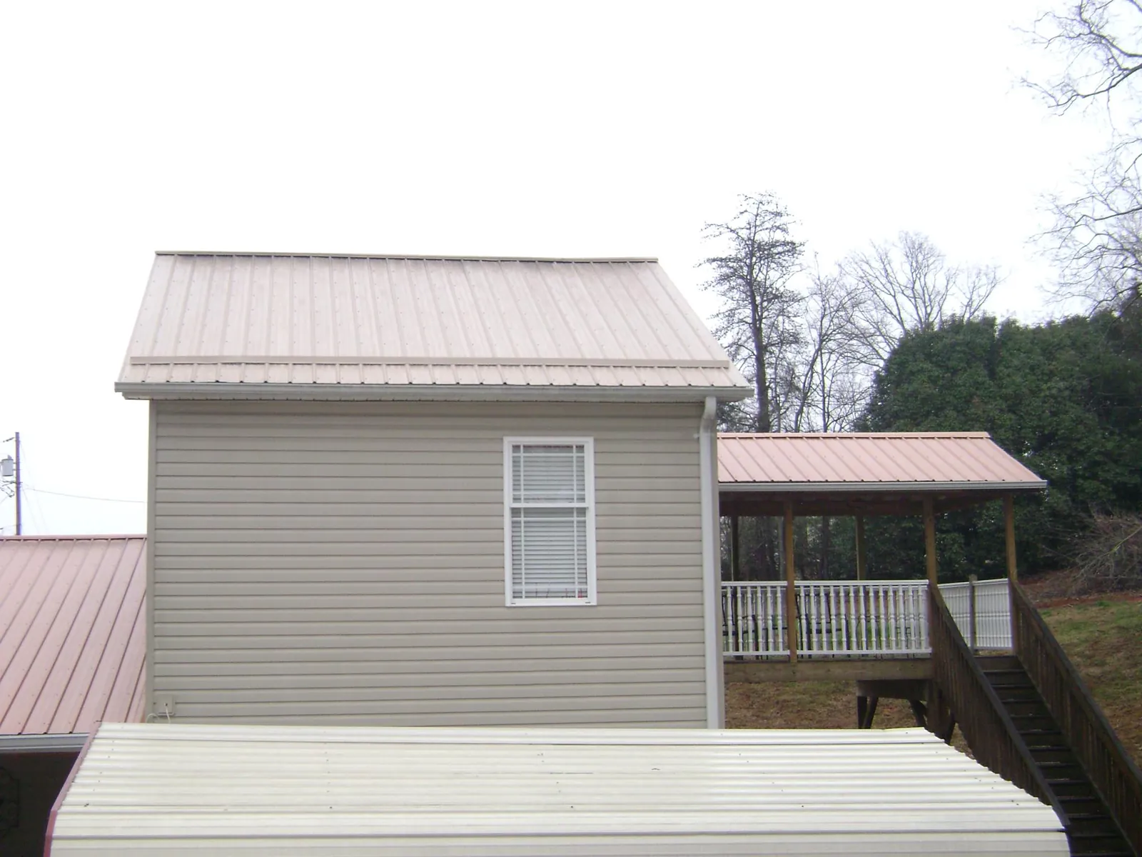 Tan metal roofs on a two story addition and attached porch, from a Roof Replacement job in Lamont