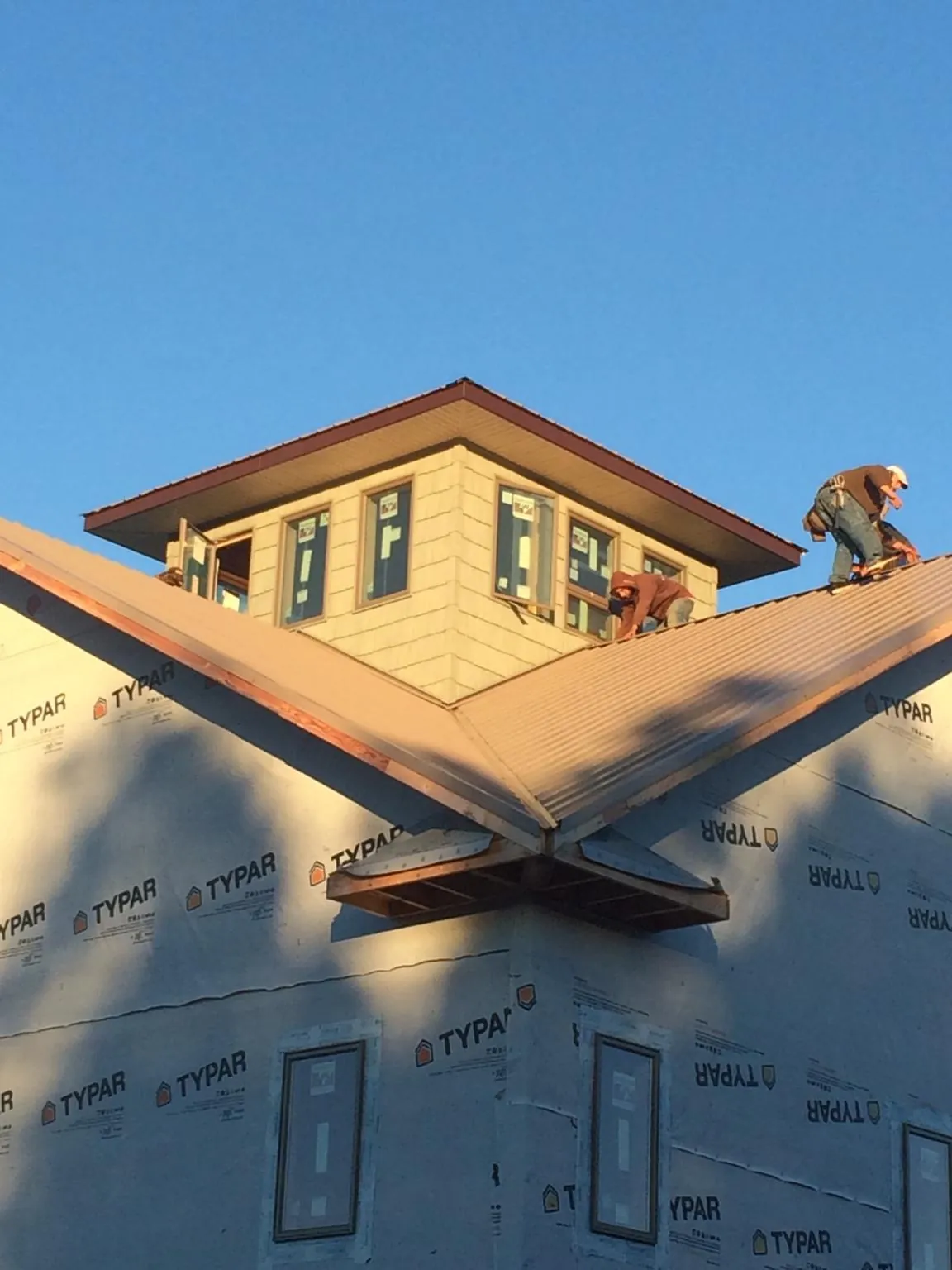 Roofers working around a rooftop cupola on a new metal roof at sunset — Roof Waterproofing in Lamont by Roofing Brothers